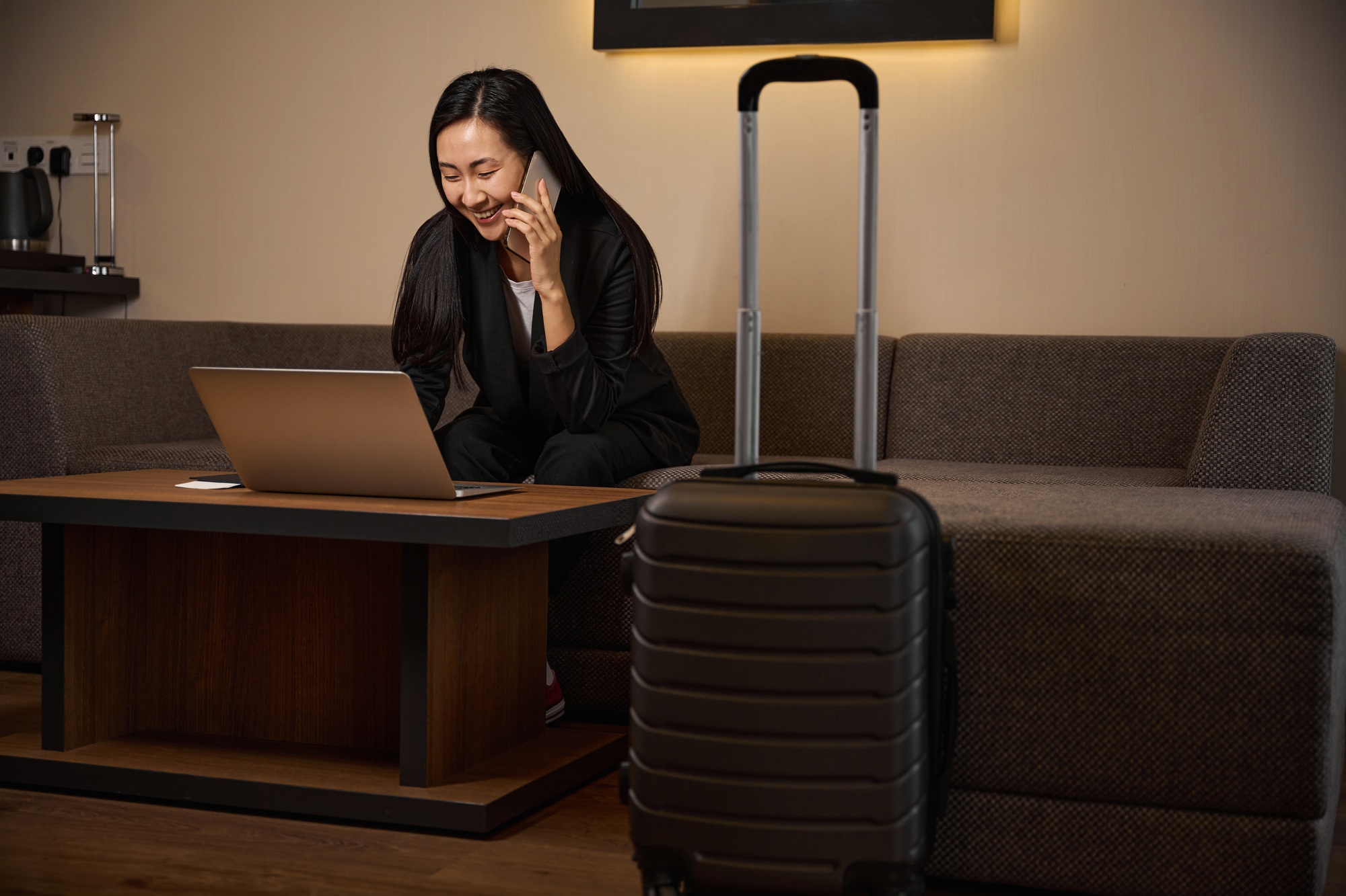 Smiling female talking on a smartphone in hotel room
